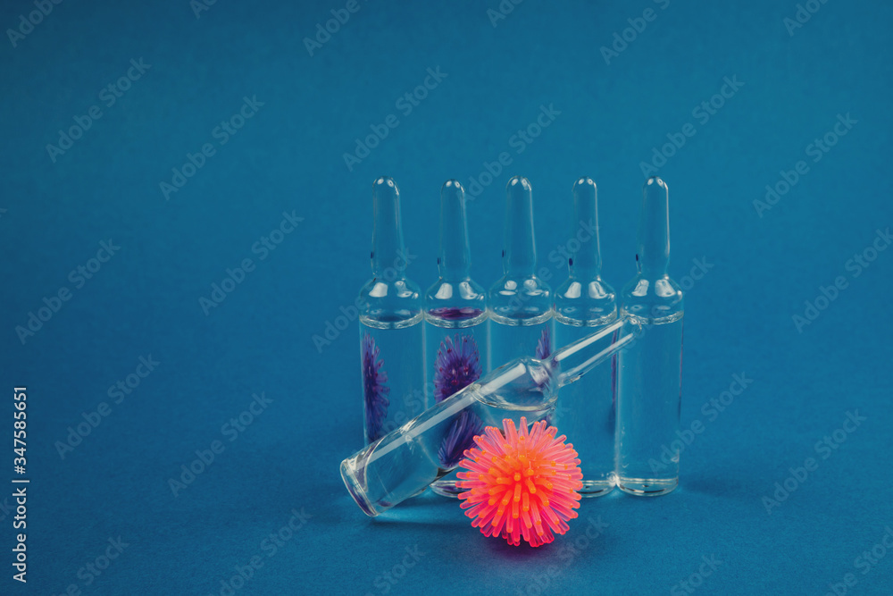 Abstract model of coronavirus and ampoule with medicine on a blue background. Abstract model of coronavirus and ampoule with medicine on a blue background.