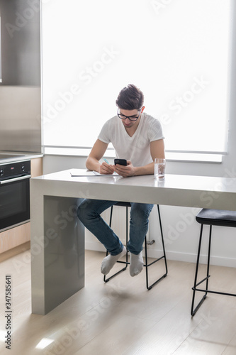 Young handsome man make notice from phone at home desk