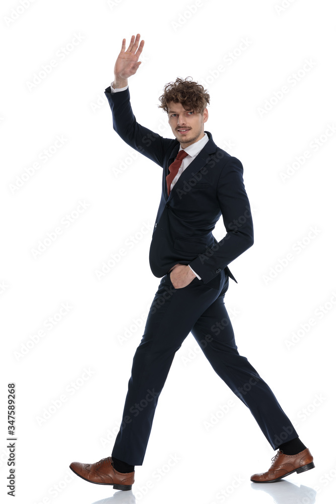 Side view of positive businessman waving with hand in pocket Side view of positive businessman waving with hand in pocket