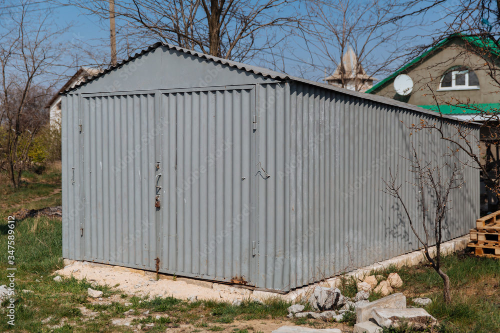 Gray old metal garage for a car, standing on the street Gray old metal garage for a car, standing on the street