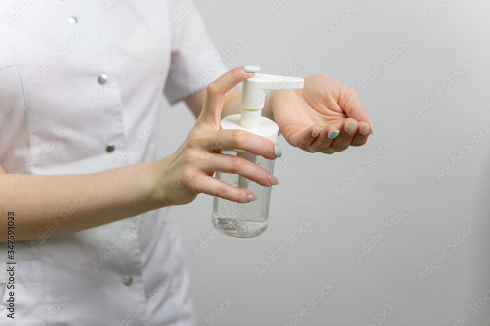 The girl is holding a liquid in a bottle. A doctor in a medical gown applies a disinfectant to his hands against bacteria and viruses. A nurse in white applies an antibacterial agent to her hands. The girl is holding a liquid in a bottle. A doctor in a medical gown applies a disinfectant to his hands against bacteria and viruses. A nurse in white applies an antibacterial agent to her hands.