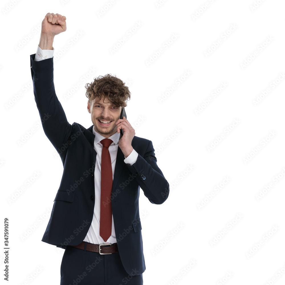 Businessman talking on phone, celebrating with fist in the air Businessman talking on phone, celebrating with fist in the air