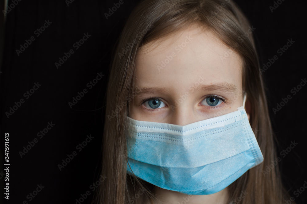 Studio portrait of little blond girl on black backgound in blue surgical disposable mask for protection of Coronavirus Covid-19 during self-isolation while stay home Studio portrait of little blond girl on black backgound in blue surgical disposable mask for protection of Coronavirus Covid-19 during self-isolation while stay home