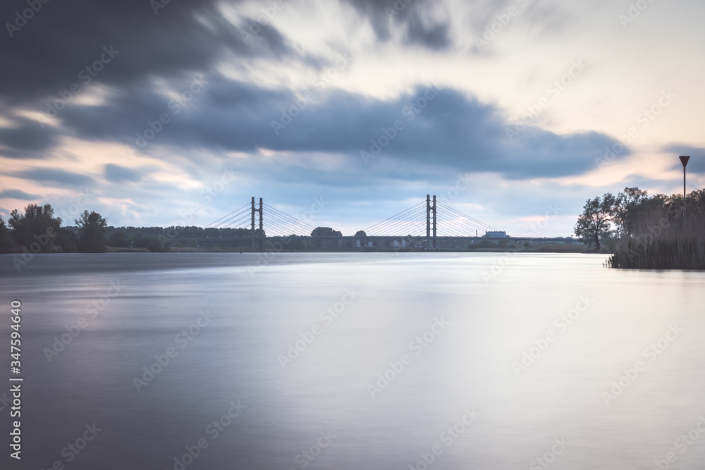 View over the water of the river IJssel with a modern cable bridge construction during nightfall
