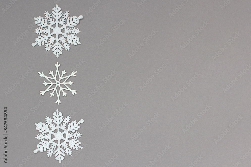 three white decorative snowflakes on a gray background. Christmas and New Year, a place for text three white decorative snowflakes on a gray background. Christmas and New Year, a place for text