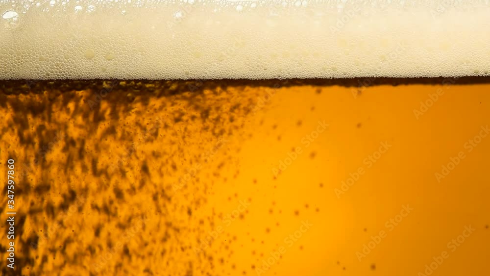 Close up pouring beer with bubbles in glass Close up pouring beer with bubbles in glass