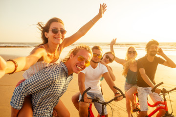 young cheerful friends self photographing on smartphone camera on the beach at sunset sunlight summer vacation