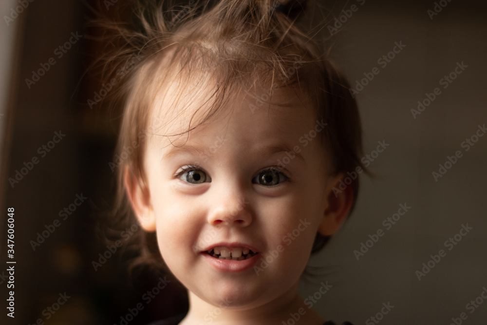 Close-up portrait of a little cute white baby with a dirty face in soft light and blurry background