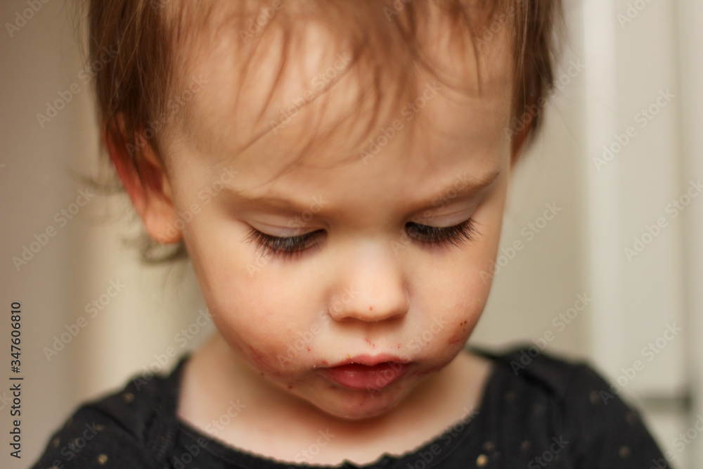 Close-up portrait of a little cute white baby with a dirty face in soft light and blurry background Close-up portrait of a little cute white baby with a dirty face in soft light and blurry background