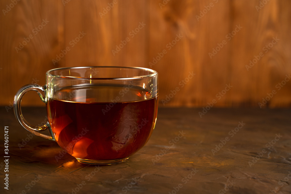 Transparent Cup with fragrant black tea on a blackboard on a natural background. Concept for your design, advertising.