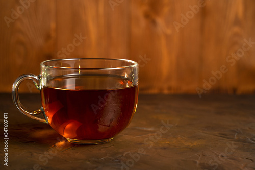 Transparent Cup with fragrant black tea on a blackboard on a natural background. Concept for your design, advertising.