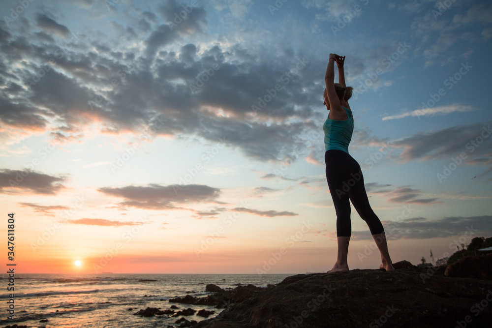 Yoga woman doing exercises on the atlantic ocean coast at twilight. Porto, Portugal.