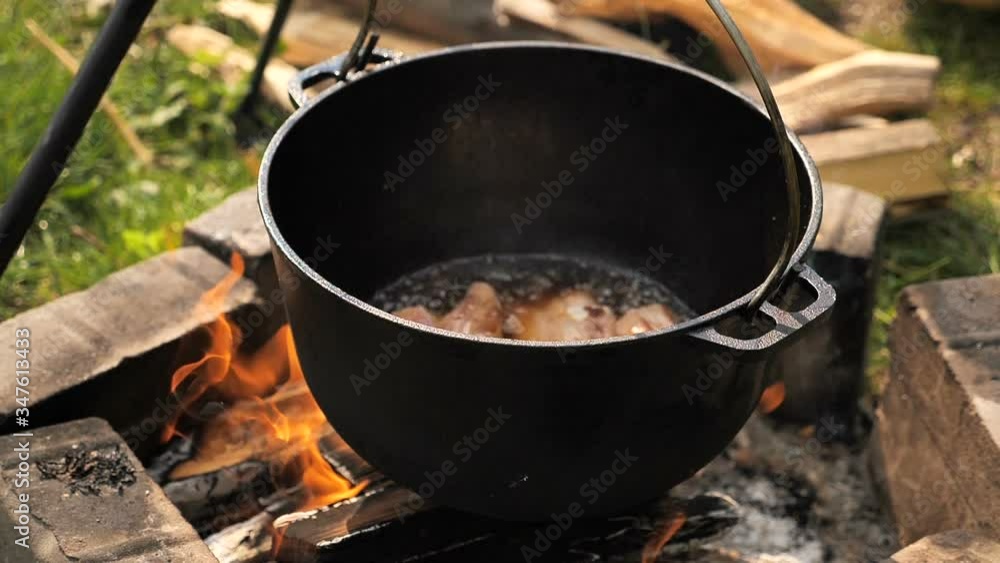 cooking meat in a cauldron on open fire . slow motion cooking meat in a cauldron on open fire . slow motion