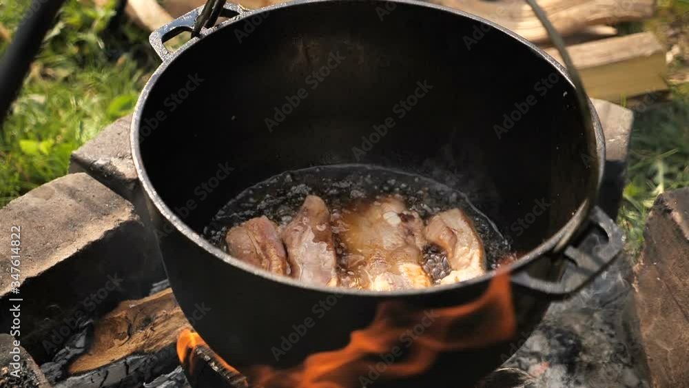cooking meat in a cauldron on open fire . slow motion cooking meat in a cauldron on open fire . slow motion