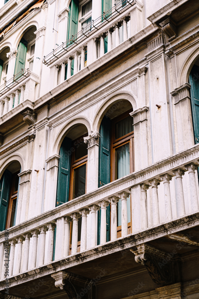 Close-ups of buildings in Venice, Italy. Incredibly beautiful stone facades of buildings in the Venetian style - stone arched windows with columns and balconies, with small details of sculptures