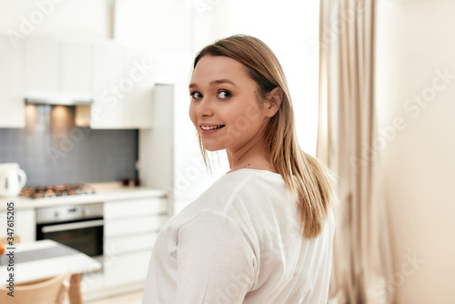 Positive vibes. Close up of young smiling woman looking at camera while going to prepare breakfast in the kitchen after a good night sleep