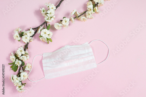 flowering branches with a medical mask on a pink background coronavirus COVID-19 in spring, 2020
