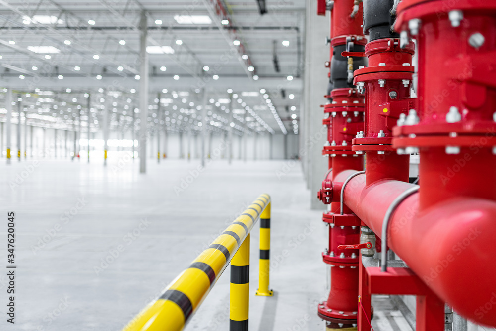 fire suppresion system in a empty industrial hall red pipes and bariers