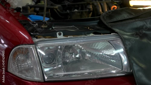 Close up car headlight with opened hood. Enginge repair in a car service. photo