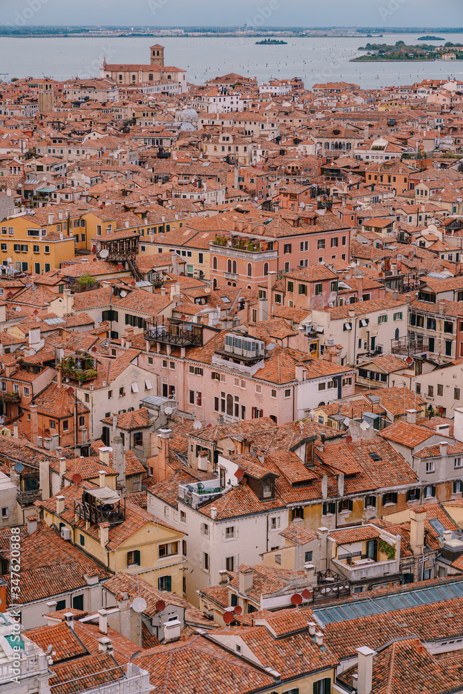 Aerial panoramic view from cathedral bell tower San Marco Campanile of old historical city centre, sea, red tiled roofs and palaces. Venice, Italy - is a popular tourist destination of Europe. 