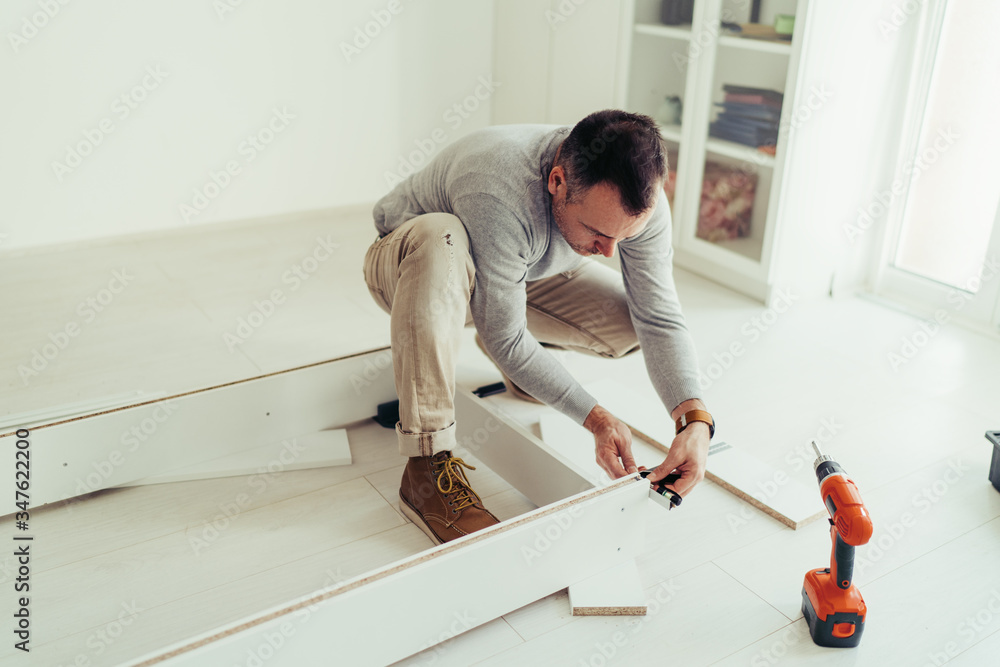 Man putting together self assembly furniture in his new home. Man putting together self assembly furniture in his new home.