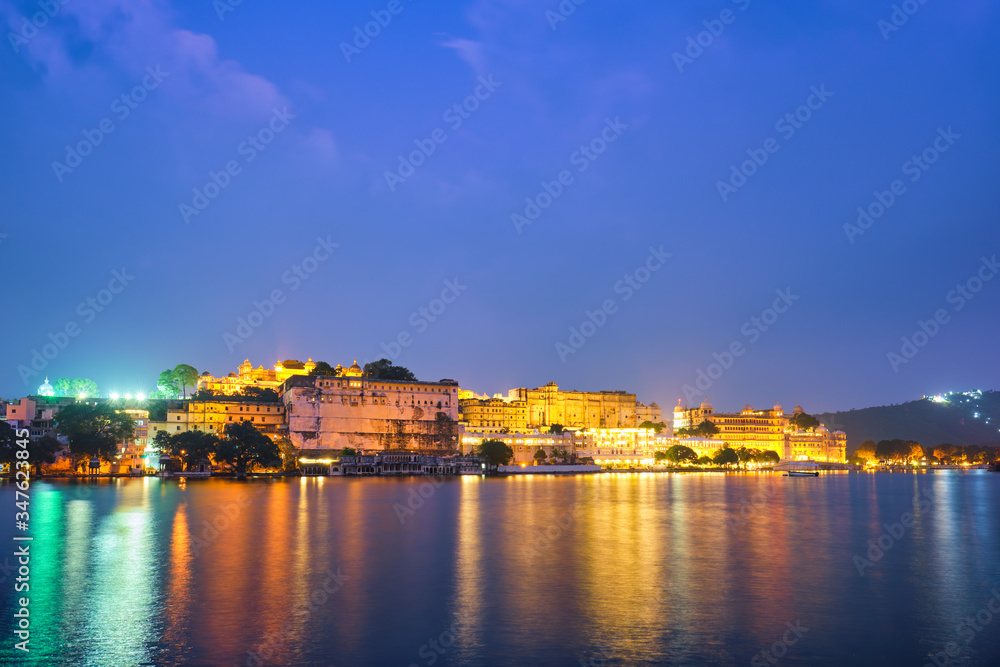 View of famous romantic luxury Rajasthan indian tourist landmark - Udaipur City Palace in the evening twilight with dramatic sky - panoramic view. Udaipur, India