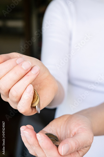 Female hand pours a small handful of coins into his palm. Concept of crisis and saving money.