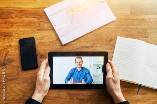 Video call on tablet screen. Male hands are holding digital tablet, a man in shirt on the screen. Online meeting, online communication