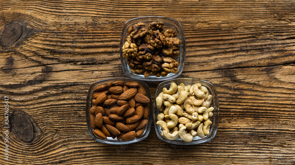 Almond, walnut and cashew in a small plates which standing on a wooden vintage table. Nuts is a healthy vegetarian protein and nutritious food. Nuts on rustic old wood. Almond, walnut and cashew in a small plates which standing on a wooden vintage table. Nuts is a healthy vegetarian protein and nutritious food. Nuts on rustic old wood.