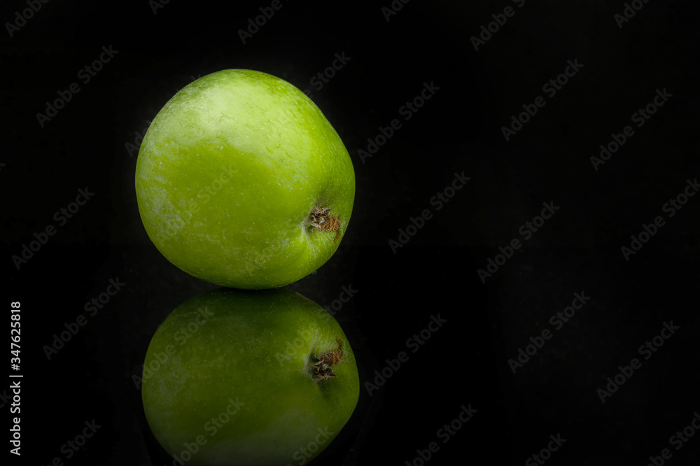 Green apple with reflection on a black background Green apple with reflection on a black background