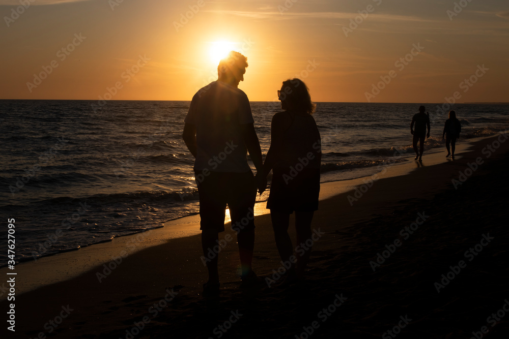 Para ludzi oglądający zachód słońca nad morzem.