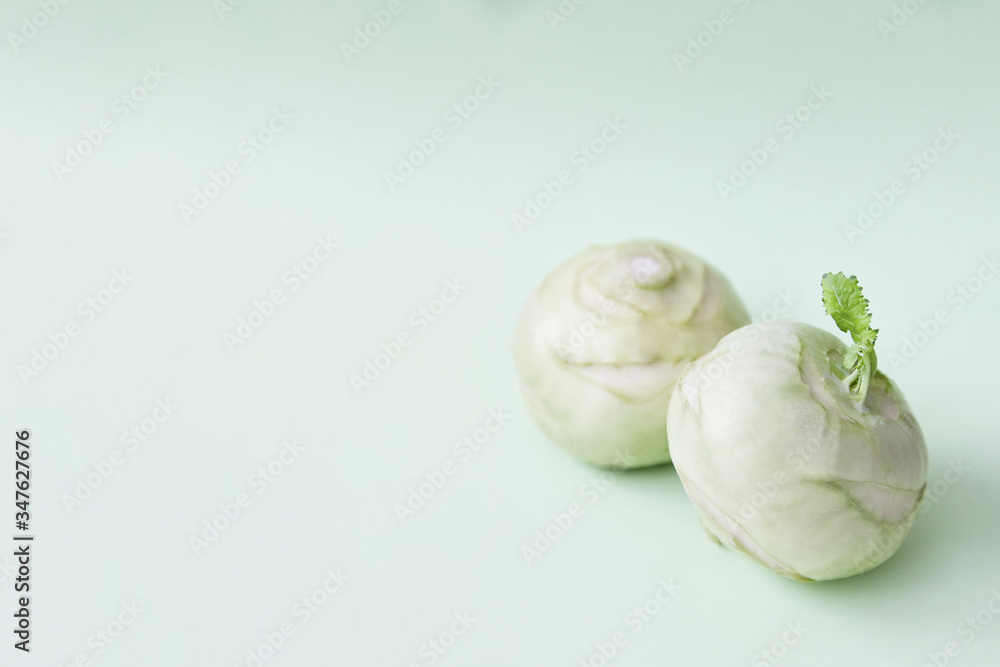 Fototapeta premium Two kohlrabies on a paper background. Light mint green background. Wallpaper. Copy space, space for text