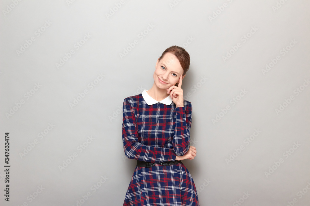 Portrait of happy young woman touching temple with finger and smiling Portrait of happy young woman touching temple with finger and smiling