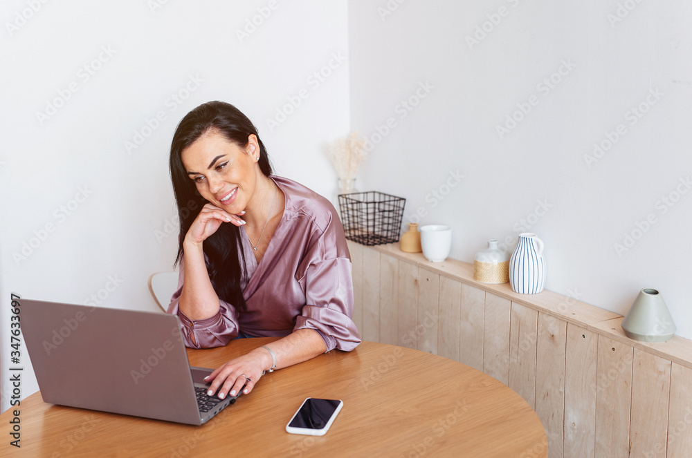 Affectionate woman looking at her laptop working from home in the kitchen Affectionate woman looking at her laptop working from home in the kitchen