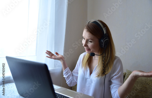 young american teen girl wear headphones video calling on laptop. pretty woman student looking at computer screen watching webinar or doing video chat by webcam photo
