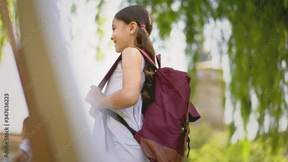 Girl student stands in a blue dress and hair ponytails with a backpack ...