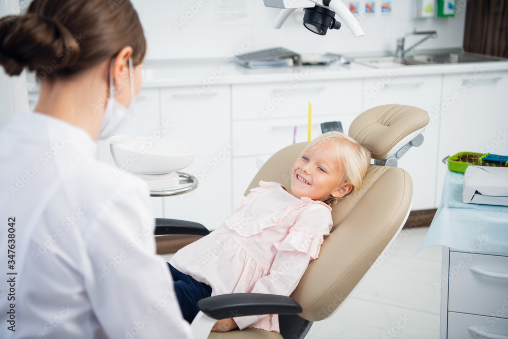 Skillful dentist is examining the teeth of a child. The woman is Skillful dentist is examining the teeth of a child. The woman is