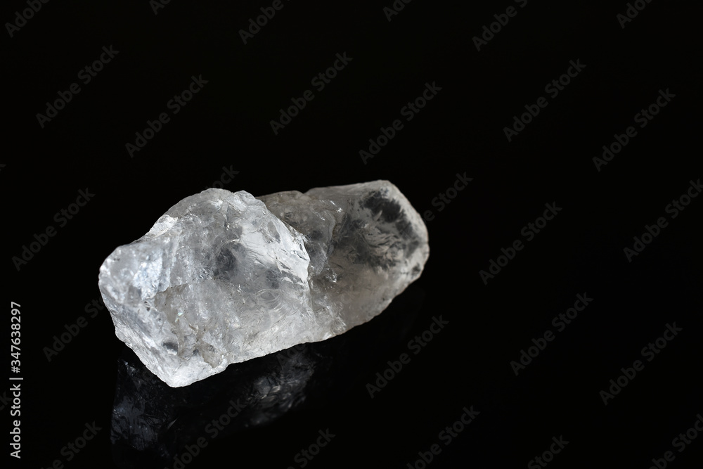 A close up image of a clear quartz crystal on a solid black background. 