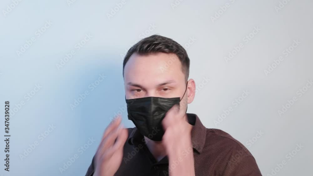 Young man puts a protective mask on his face. Young man puts a protective mask on his face.