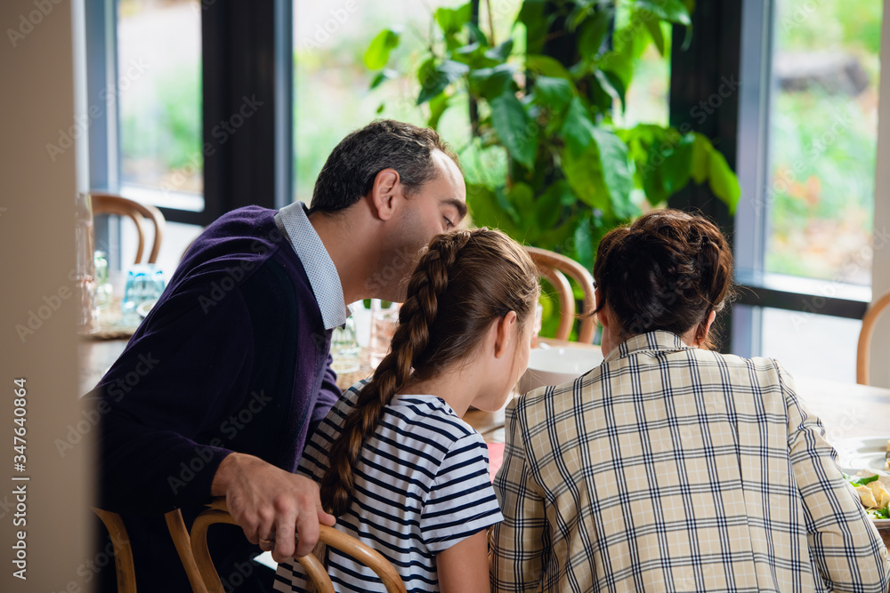 Fototapeta premium A family reading something at the kitchen table, view from the b