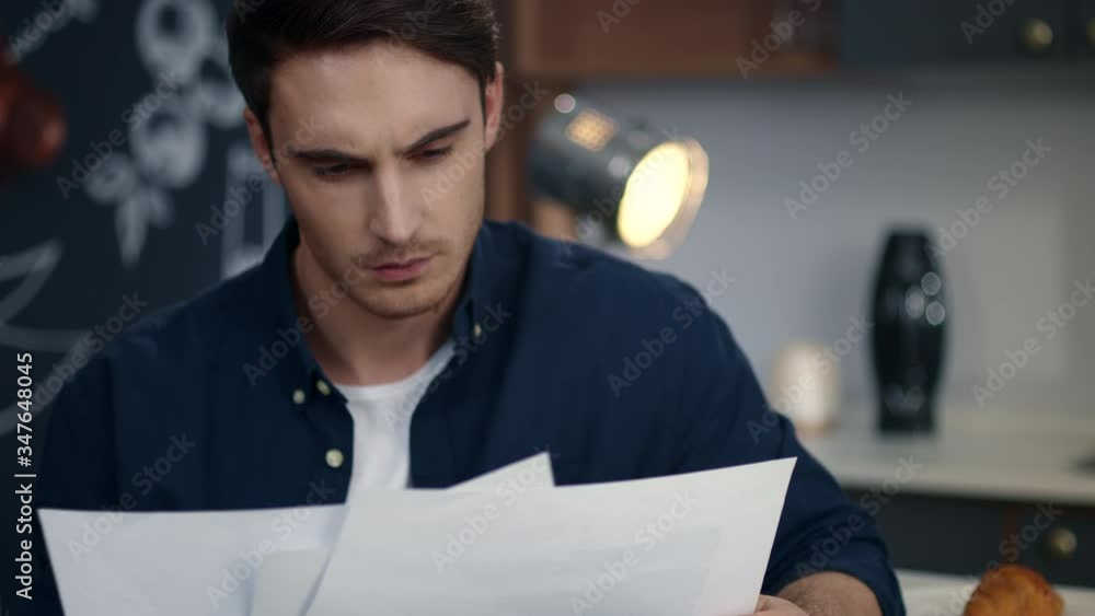 Focused business man looking on diagrams at home office. Man reading documents