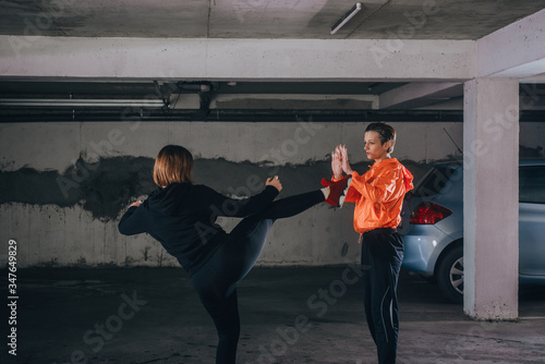 Two female athletes showing technical skills while practicing fighting in a garage © qunica.com