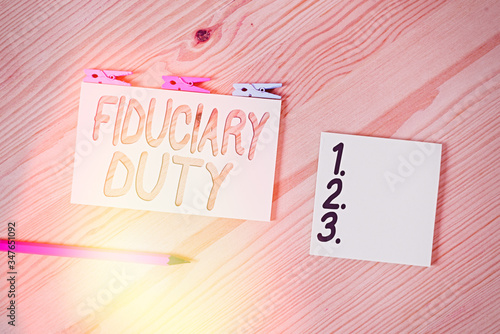 Conceptual hand writing showing Fiduciary Duty. Concept meaning A legal obligation to act in the best interest of other Colored crumpled papers wooden floor background clothespin photo