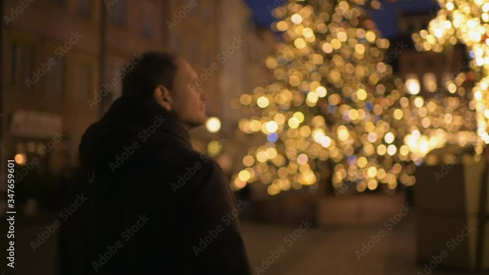Man tourist travel walking in Warsaw, Poland old town market square Warszawa at night with Christmas illumination decoration ice rink bokeh background lights Man tourist travel walking in Warsaw, Poland old town market square Warszawa at night with Christmas illumination decoration ice rink bokeh background lights