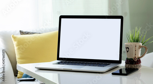 Mockup blank screen laptop with smartphone, mug and houseplant on white wooden top table in living room.