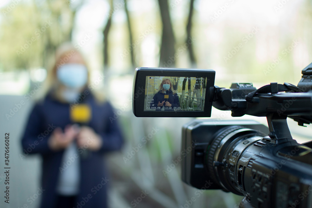 A female journalist in a protective medical mask is reporting in a deserted city. Concept of protection against dangerous coronavirus. TV report on the epidemic.