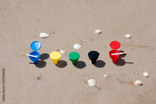 Composizione di posacenere colorati sulla spiaggia, con conchiglie sullo sfondo photo