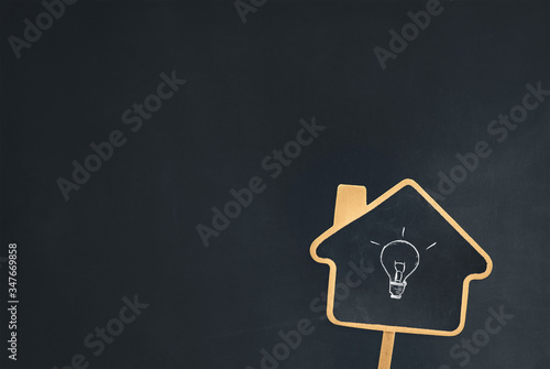 a house sign chalkboard with a light bulb symbol showing idea of knowledge gained from homeschooling education. studying class or learning from a tutoring course. blank blackboard background for text.
