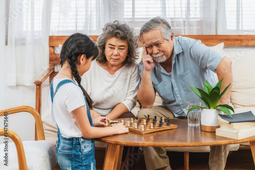 Asian couple Grandparent with grandchild playing the chess with Use thought together