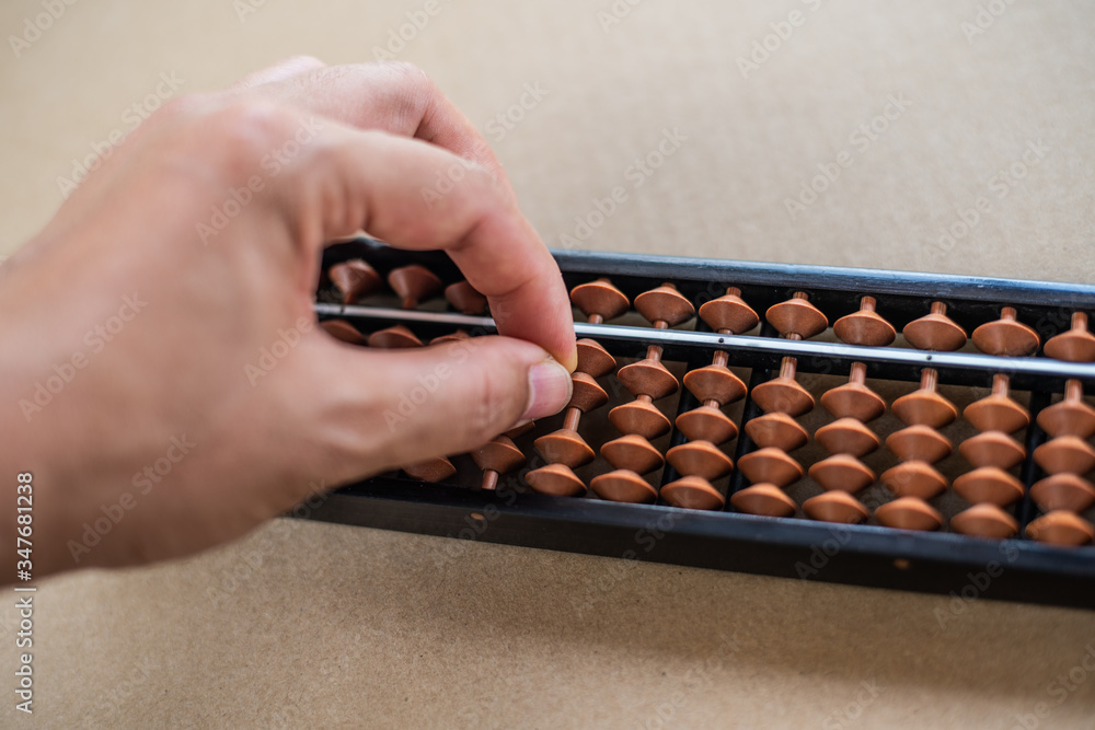 Hand using abacus on wood texture. Hand using abacus on wood texture.